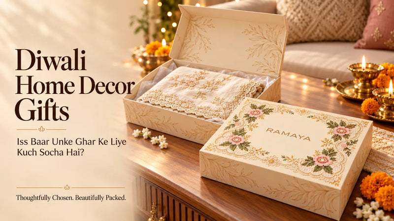 Diwali home decor gift ideas featuring an embroidered table runner, matching placemats, brass diyas and marigold flowers, with a cushion-styled sofa in the background.