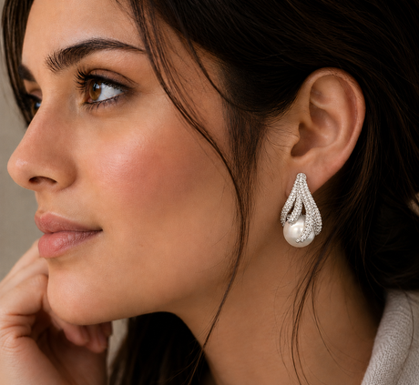 Close-up of a woman wearing a pearl earring with a neutral background