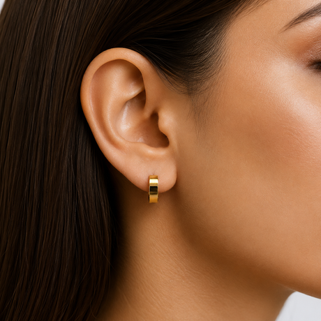 Close-up of a person wearing a gold hoop earring.