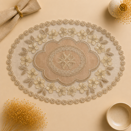 An oval beige and cream embroidered table runner with intricate lace and floral detailing, styled in a flat-lay composition on a matching beige background with decorative props.