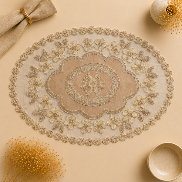 An oval beige and cream embroidered table runner with intricate lace and floral detailing, styled in a flat-lay composition on a matching beige background with decorative props.