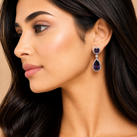 Close-up of a woman wearing purple teardrop earrings with a neutral background