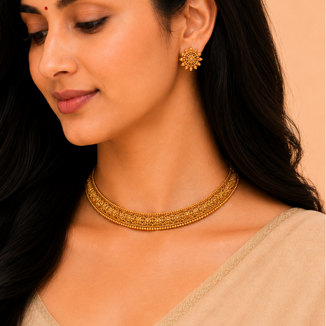 Woman wearing gold jewelry including a necklace and earrings against a beige background
