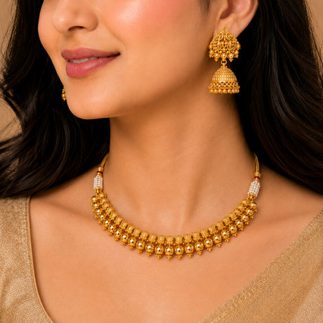 Woman wearing a gold necklace and earrings on a beige background