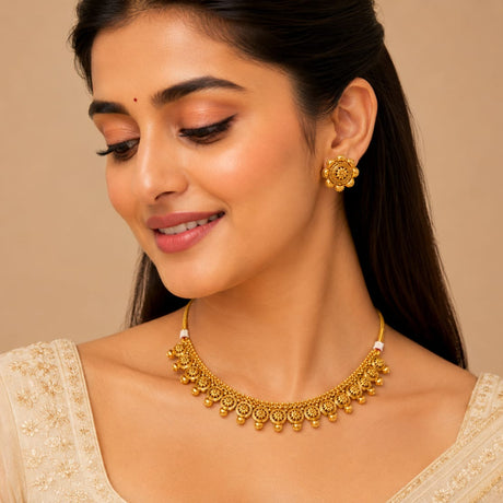 Woman wearing gold jewelry including a necklace and earrings against a beige background