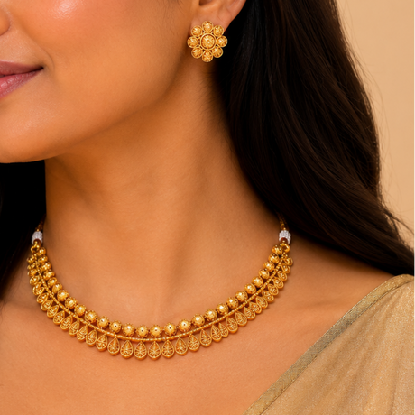 Woman wearing gold jewelry including earrings and a necklace against a beige background