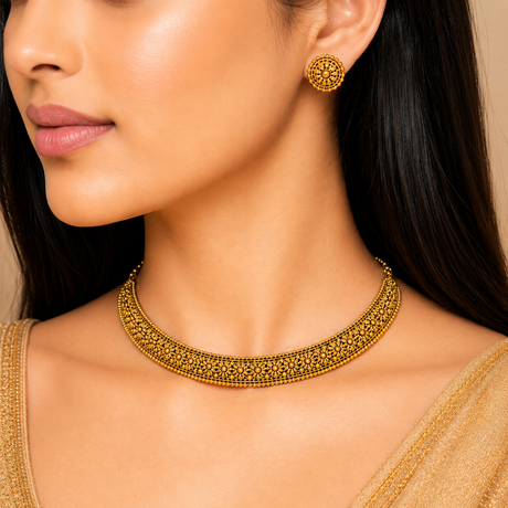 Close-up of a woman wearing gold jewelry including a necklace and earrings.