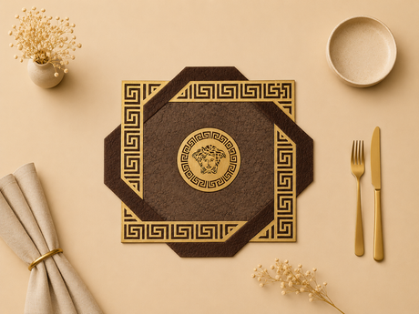 Decorative placemat with gold patterns on a beige surface with cutlery and flowers.