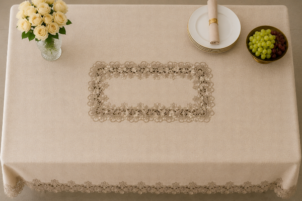 Beige tablecloth with lace trim on a table set with a vase of flowers, plates, and grapes.