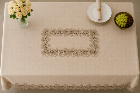 Beige tablecloth with lace trim on a table set with a vase of flowers, plates, and grapes.