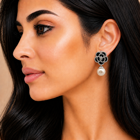 Close-up of a woman wearing a floral earring with a pearl drop.