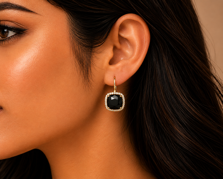 Close-up of a woman wearing a black earring with a gold setting.