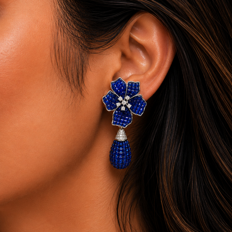 Close-up of a person wearing a blue floral earring with a dark background