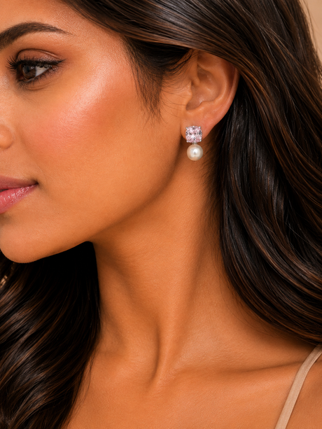 Close-up of a woman wearing pearl earrings with a neutral background