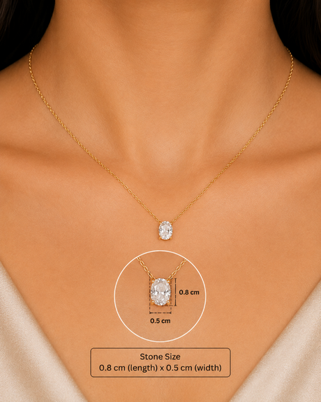 A close-up of a model's neck and chest wearing a delicate gold chain necklace with a small oval clear stone pendant. A circular inset highlights the pendant's dimensions as 0.