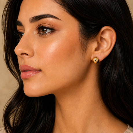 Close-up of a woman wearing gold earrings with a neutral background