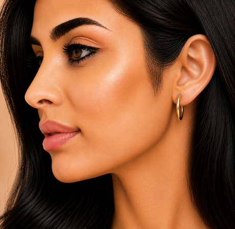 Close-up of a woman wearing a gold hoop earring with a neutral background