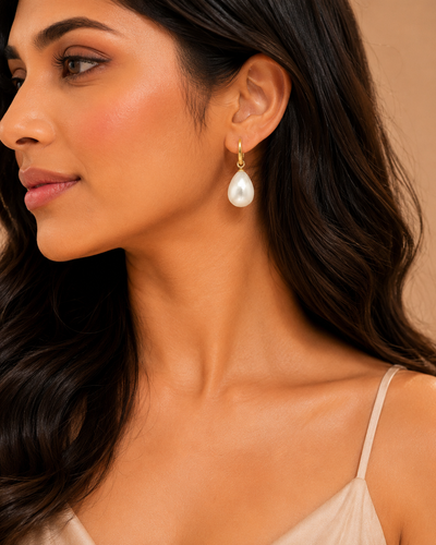 Close-up of a woman wearing pearl earrings with a neutral background