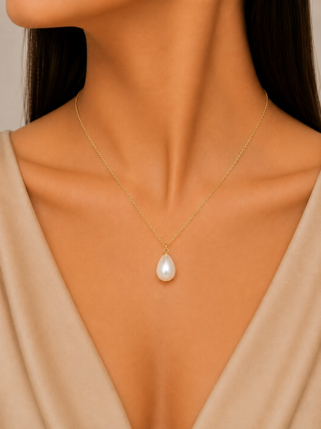 Gold necklace with a pearl pendant worn by a model against a neutral background