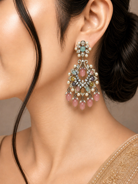 Close-up of a woman wearing a pair of ornate earrings with gemstones.