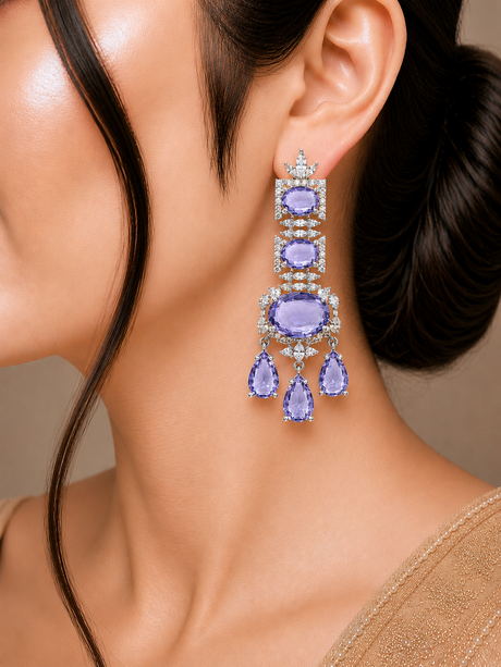 Close-up of a woman wearing a pair of purple gemstone earrings with a neutral background