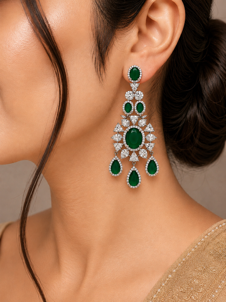 Close-up of a woman wearing emerald and diamond earrings against a neutral background