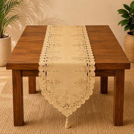 Beige embroidered table runner on a wooden table with plants in the background