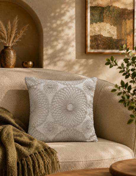 Decorative pillow on a beige armchair with a warm-toned room setting.