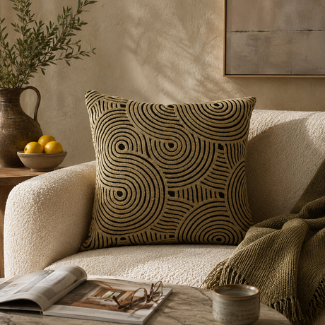 Decorative pillow with geometric pattern on a beige sofa in a cozy living room setting.