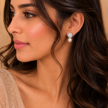 Close-up of a woman wearing pearl earrings with a neutral background