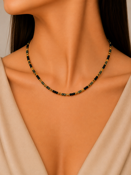 Necklace with black and gold beads on a model wearing a beige top.