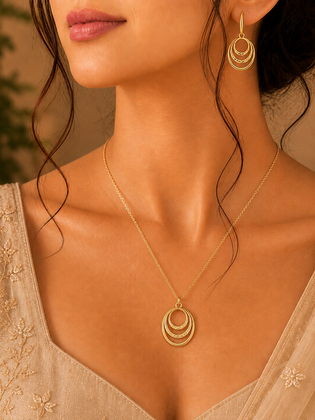 Close-up of a woman wearing a gold necklace and earrings with a neutral background