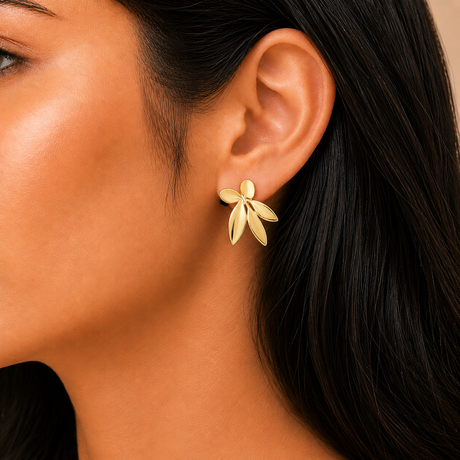 Close-up of a woman wearing a gold floral earring with a neutral background