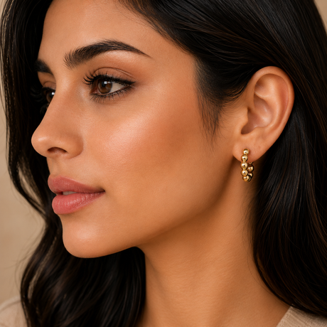 Close-up of a woman wearing gold earrings with a neutral background