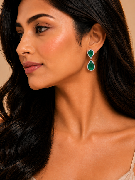 Woman wearing green teardrop earrings with a neutral background