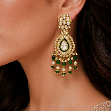 Close-up of a woman wearing a gold earring with green gemstones.