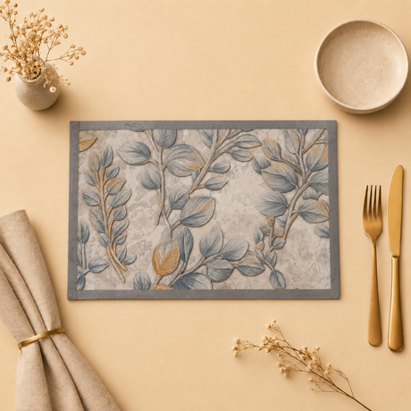 Decorative placemat with leaf pattern on a beige surface with cutlery and napkins.
