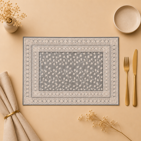 Decorative placemat with floral pattern on a beige surface with cutlery and napkin.