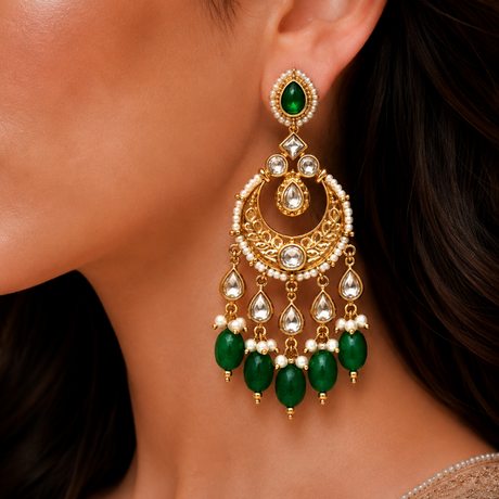 Close-up of a woman wearing gold earrings with green and white stones.