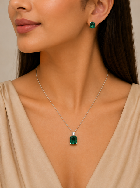 Woman wearing a necklace and earrings with emerald stones on a neutral background