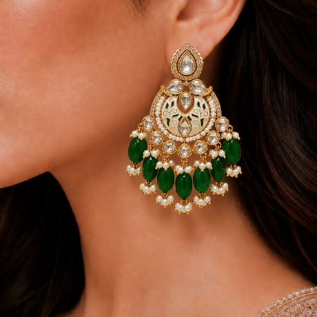 Close-up of a woman wearing a gold earring with green gemstones.