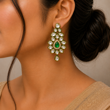 Close-up of a woman wearing a green gemstone earring with a beige garment.