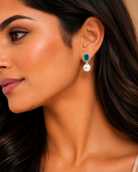 Close-up of a woman wearing emerald green and pearl earrings.