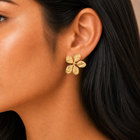 Close-up of a person wearing a gold floral earring.