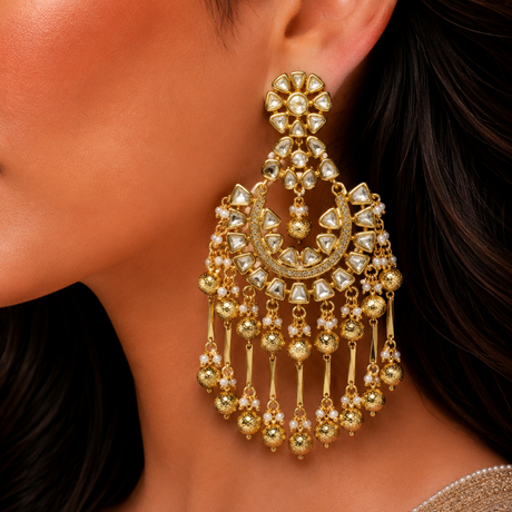 Gold earrings with dangling beads worn by a person
