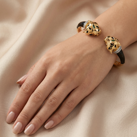 Gold and black bracelet on a hand against a beige fabric background