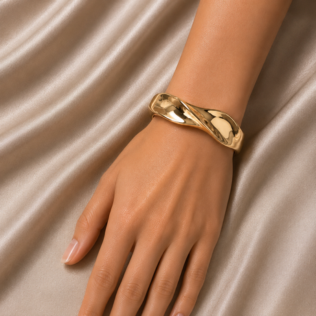 Gold bracelet on a hand against a beige fabric background