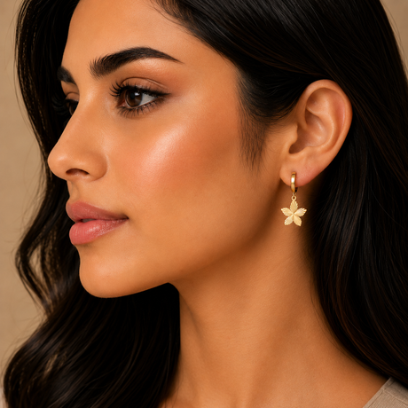 Close-up of a woman wearing a gold flower earring against a neutral background