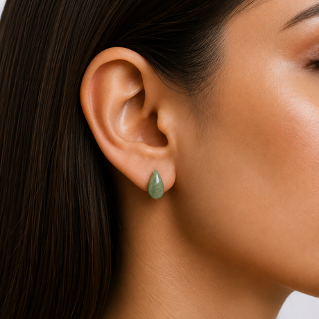 Close-up of a woman's ear wearing a green teardrop earring.