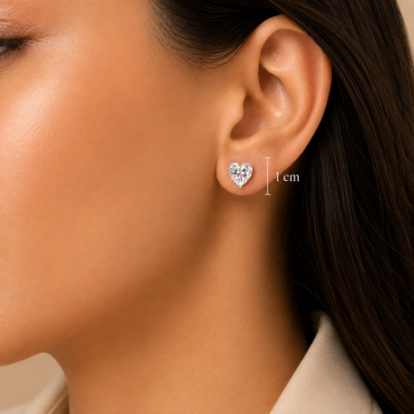 Close-up of a woman's ear wearing a small heart-shaped stud earring, with a vertical measurement marker labeled 1 cm beside the earring.